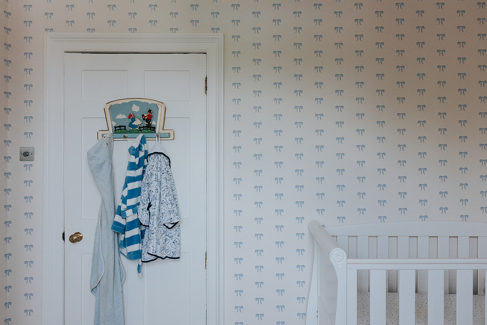 Bow wallpaper in blue lines the wall of this childs bedroom