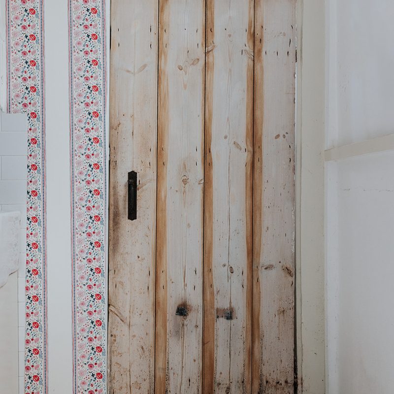 Matilda Floral Stripe Wallpaper in Pink frames a door