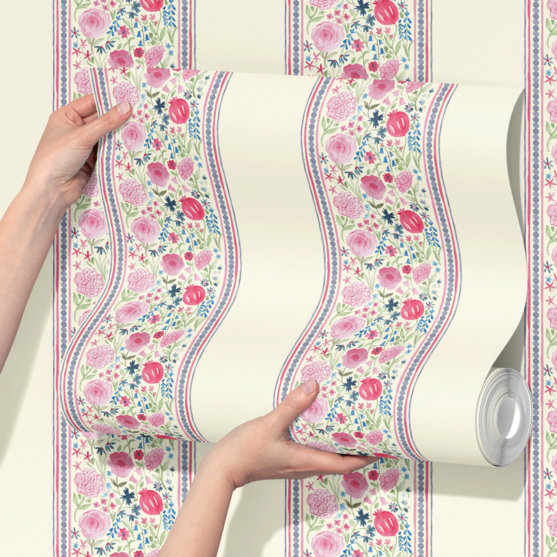 Matilda Floral Stripe wallpaper by Willow and Woods, in pink, held up by hands.