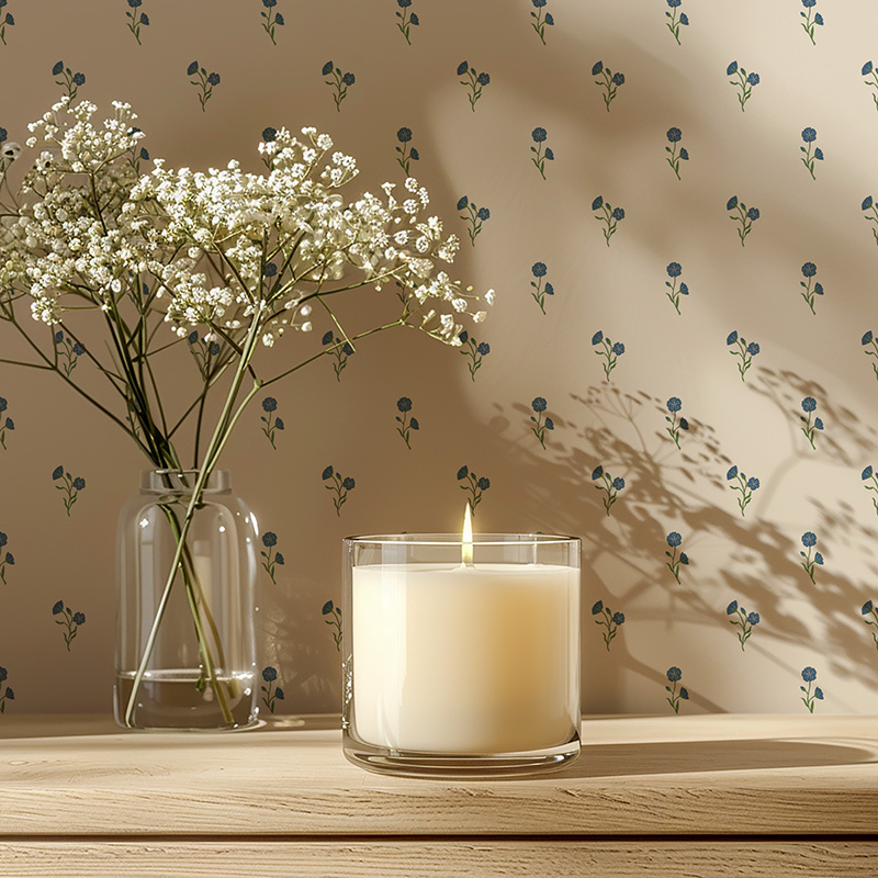 Found Flower Mist floral wallpaper with small scale hand drawn flower pattern in soft blue. decorates the wall behind a lit candle.