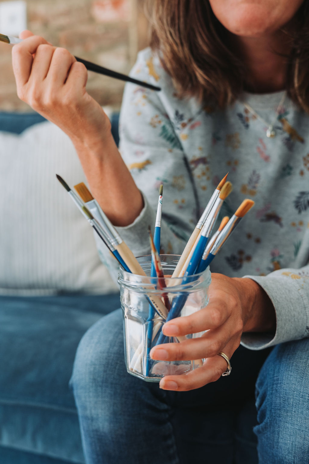 Katie holds a jar of paintbrushes