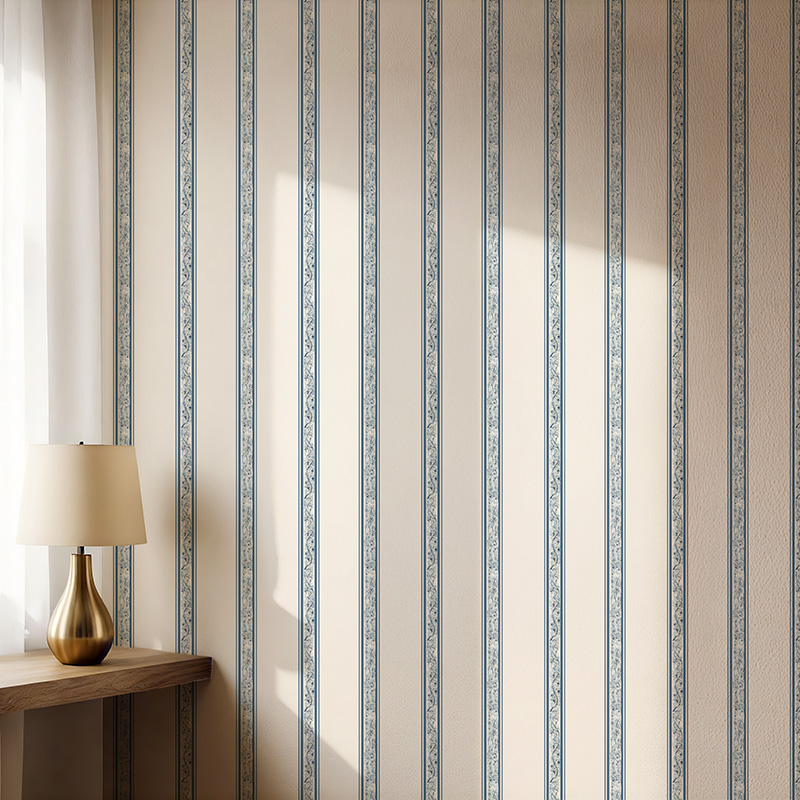 Margaret Hand Mist floral stripe wallpaper with hand drawn climbing floral pattern in tonal blue on warm neutral background decorates a wall lit by soft sunlight.